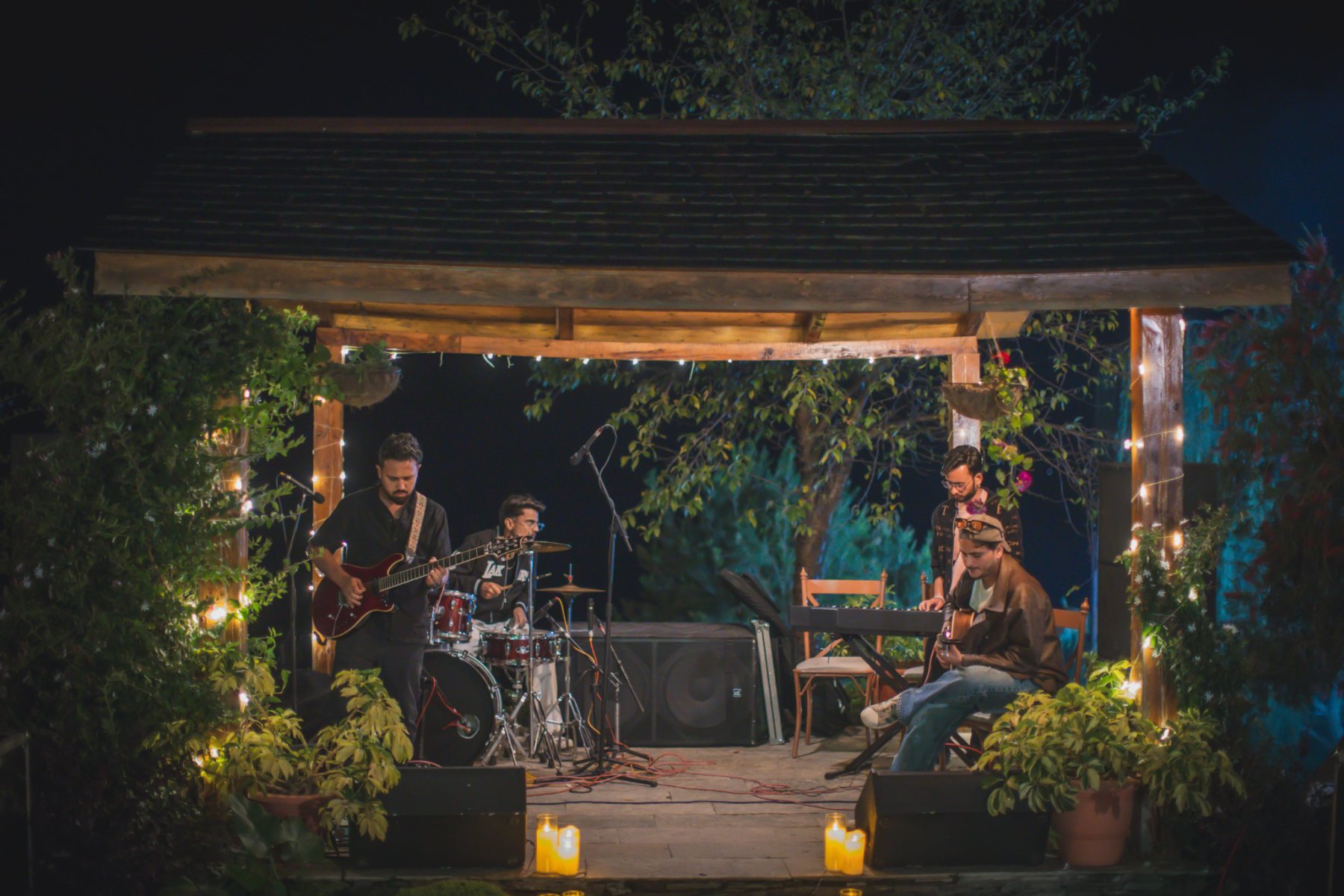 Live band with guitar, drums and keyboard performing outdoors at Auramah Valley.